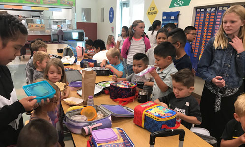 students sitting at lunch table in cafeteria 
